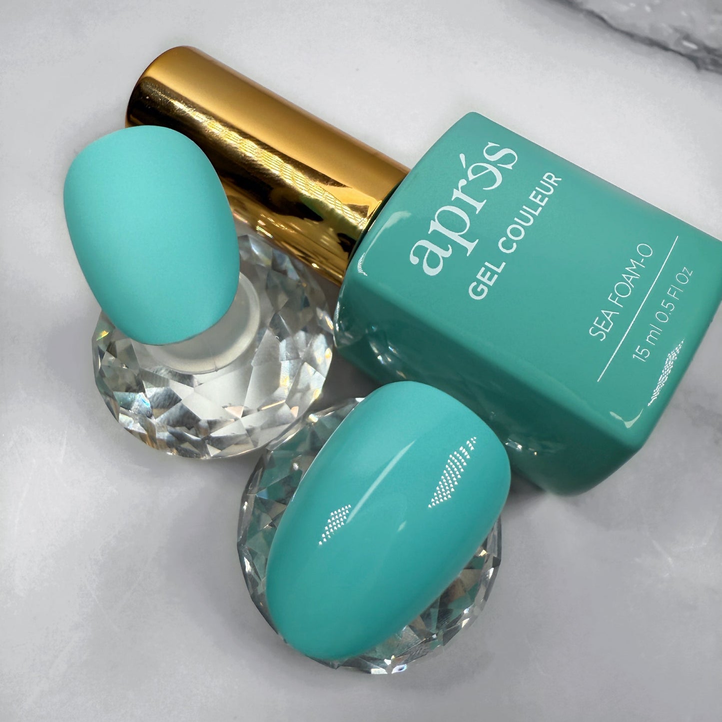 teal nail polish bottle with gold cap beside two sample nails showing matte versus glossy topcoat
