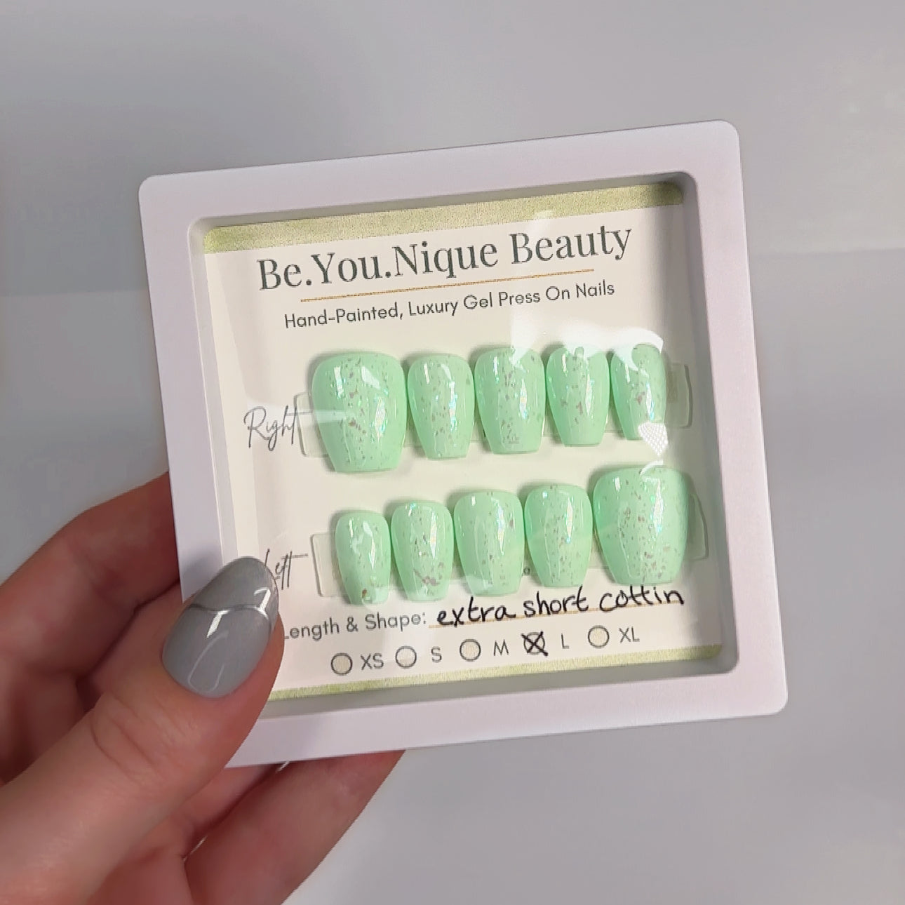 A set of extra short coffin-shaped press-on nails in size large, featuring a sparkling mint green design. The nails are coated in a fine, shimmering glitter that gives them a fresh, eye-catching glow. Pre-designed and ready for easy application with adhesive tabs, this set offers a fun and trendy manicure that's perfect for adding a pop of color and sparkle to your look.