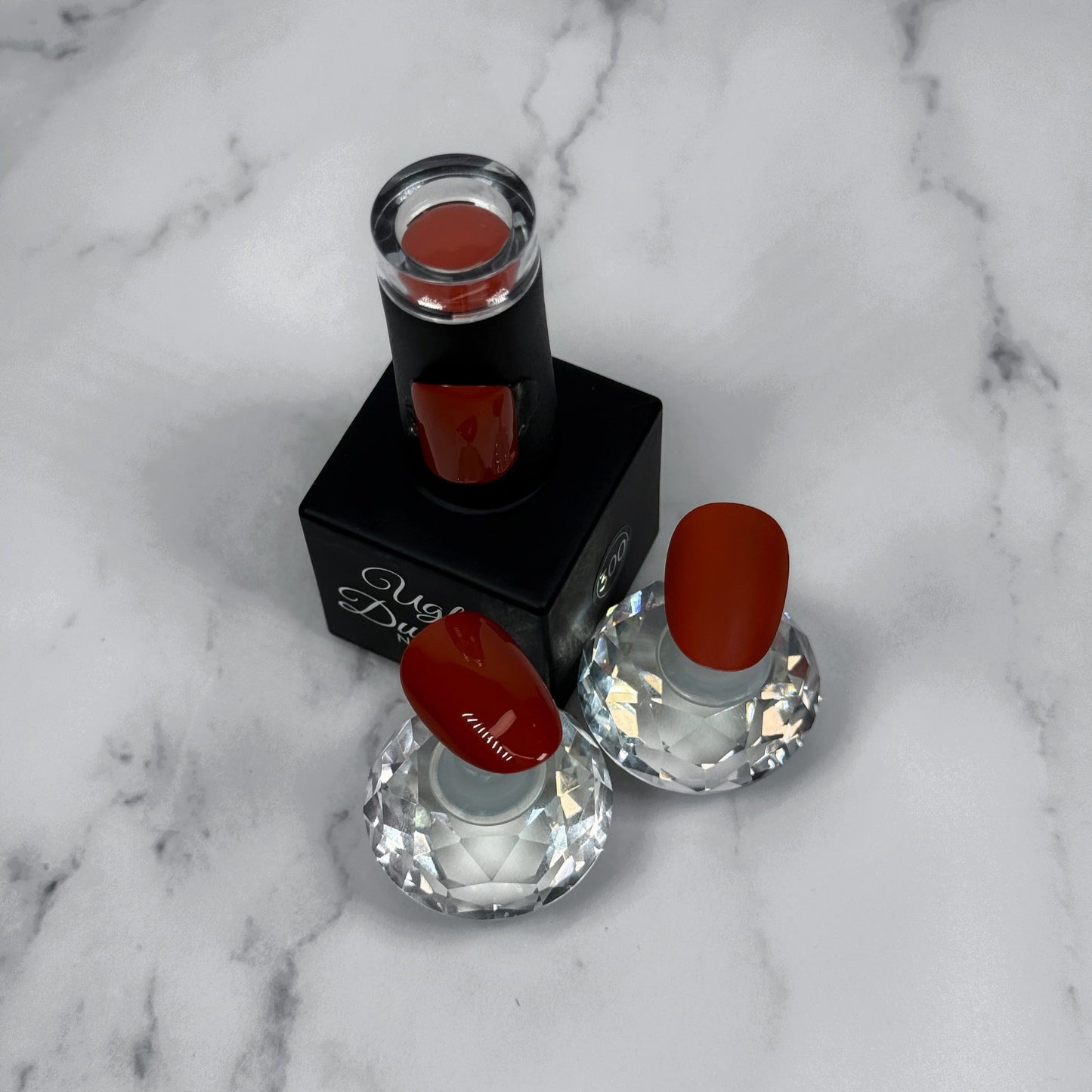 nail polish with two sample nails showing matte and glossy topcoat on a marble surface
