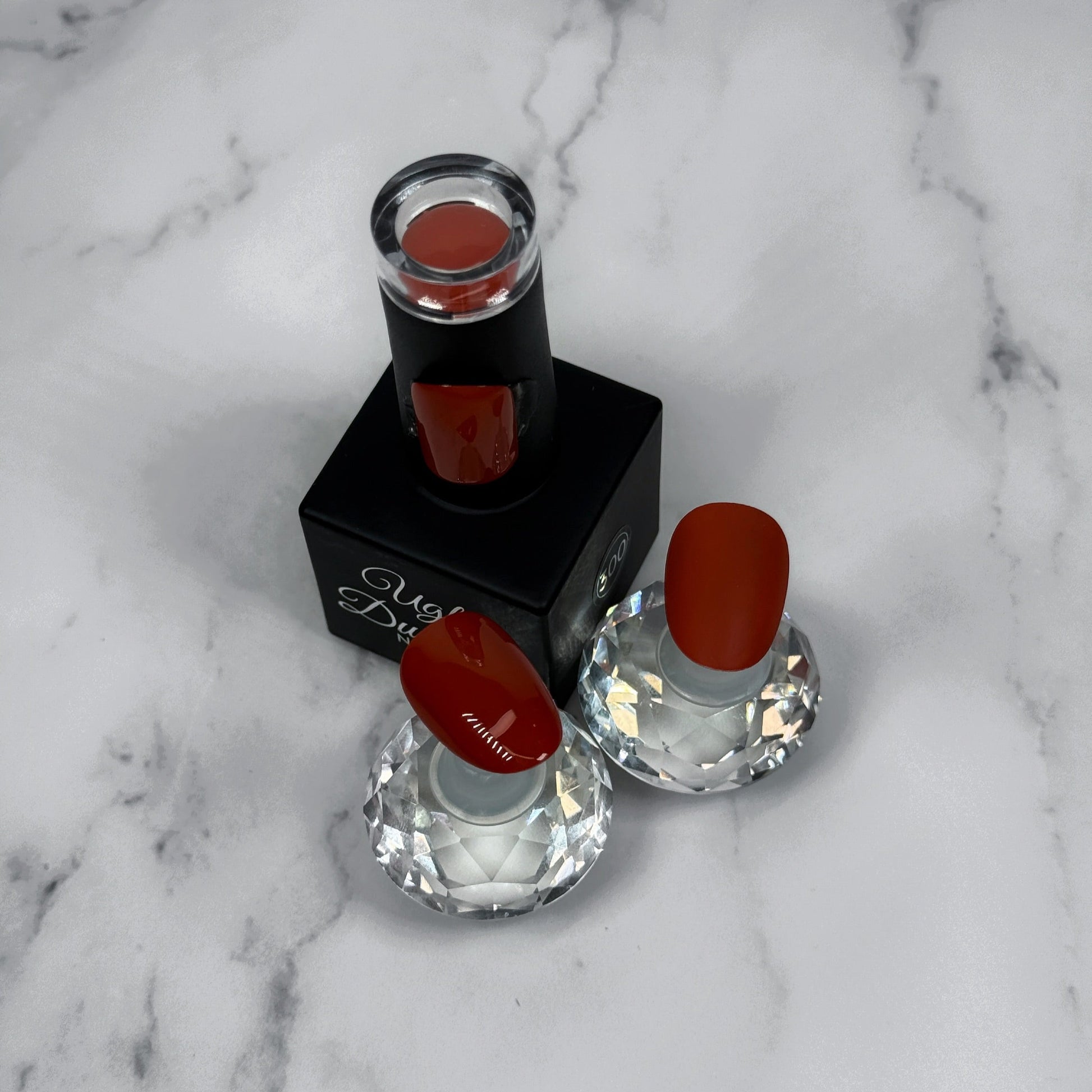 nail polish with two sample nails showing matte and glossy topcoat on a marble surface