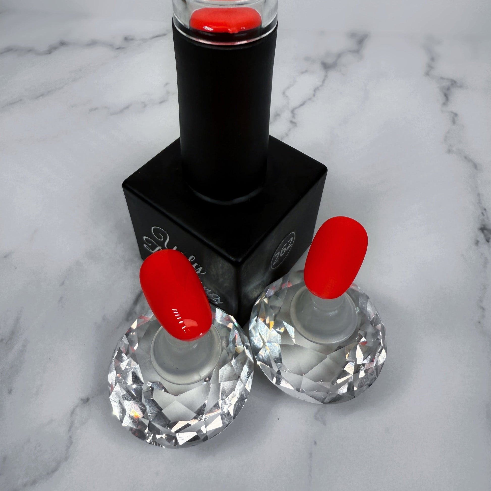 Black nail polish bottle with red sample nails showing glossy and matte topcoat on marble surface