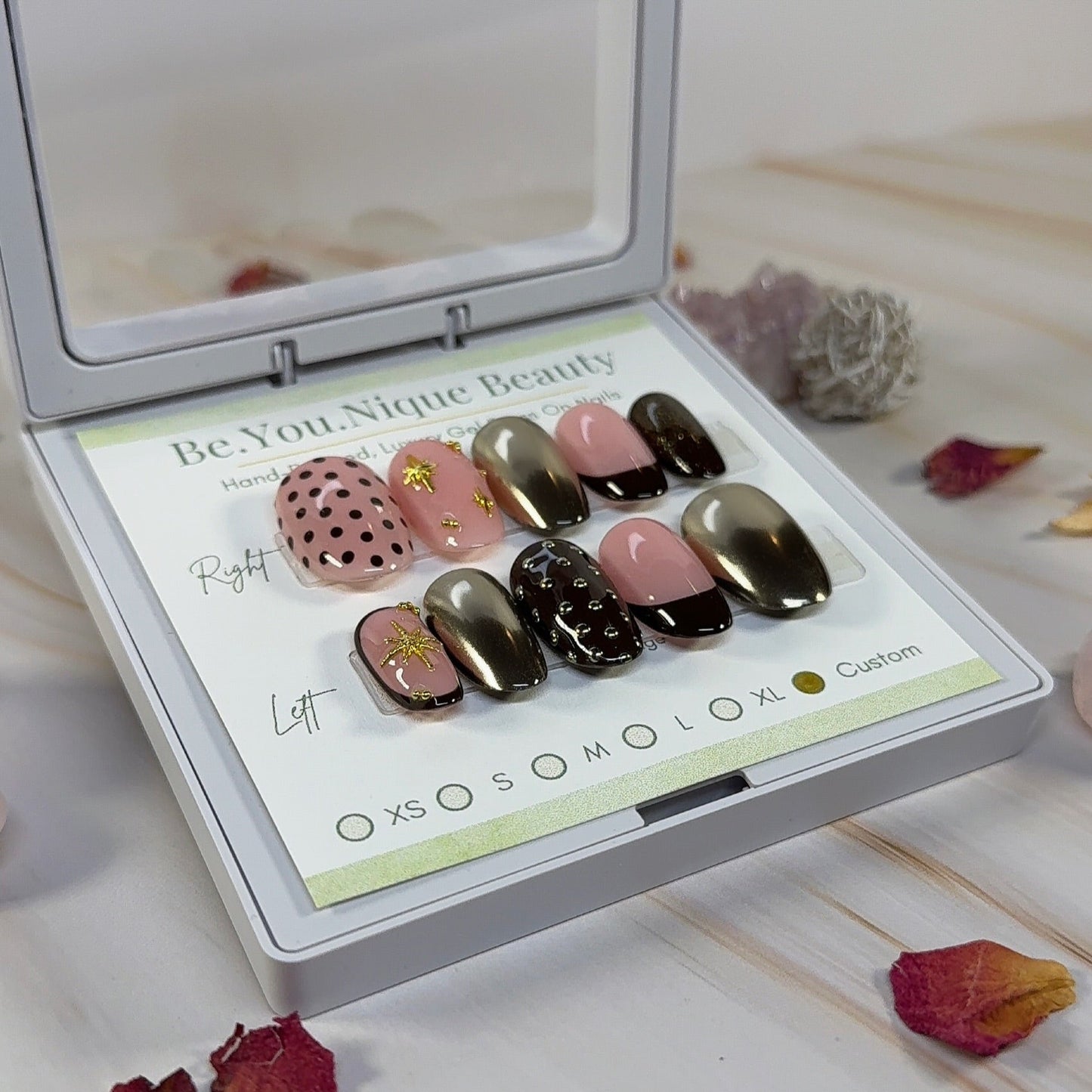 Custom Press on nail set in short round shape with a brown and gold chrome theme. this set features 3 gold chrome nails, 2 french tip nails with a deep brown tip, two nails with polka dots and 2 nails with gold star charms. the base colour is a peachy pink.