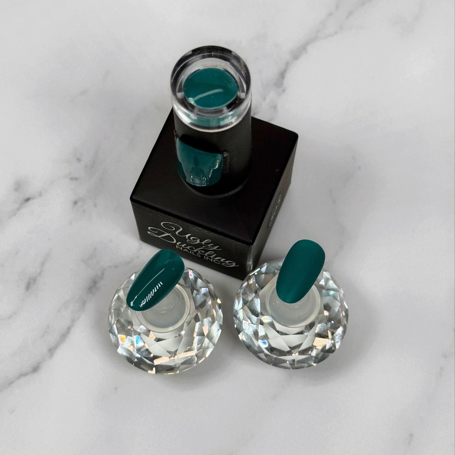 Teal Nail polish in the bottle with two sample nails showing the difference between matte and glossy topcoat