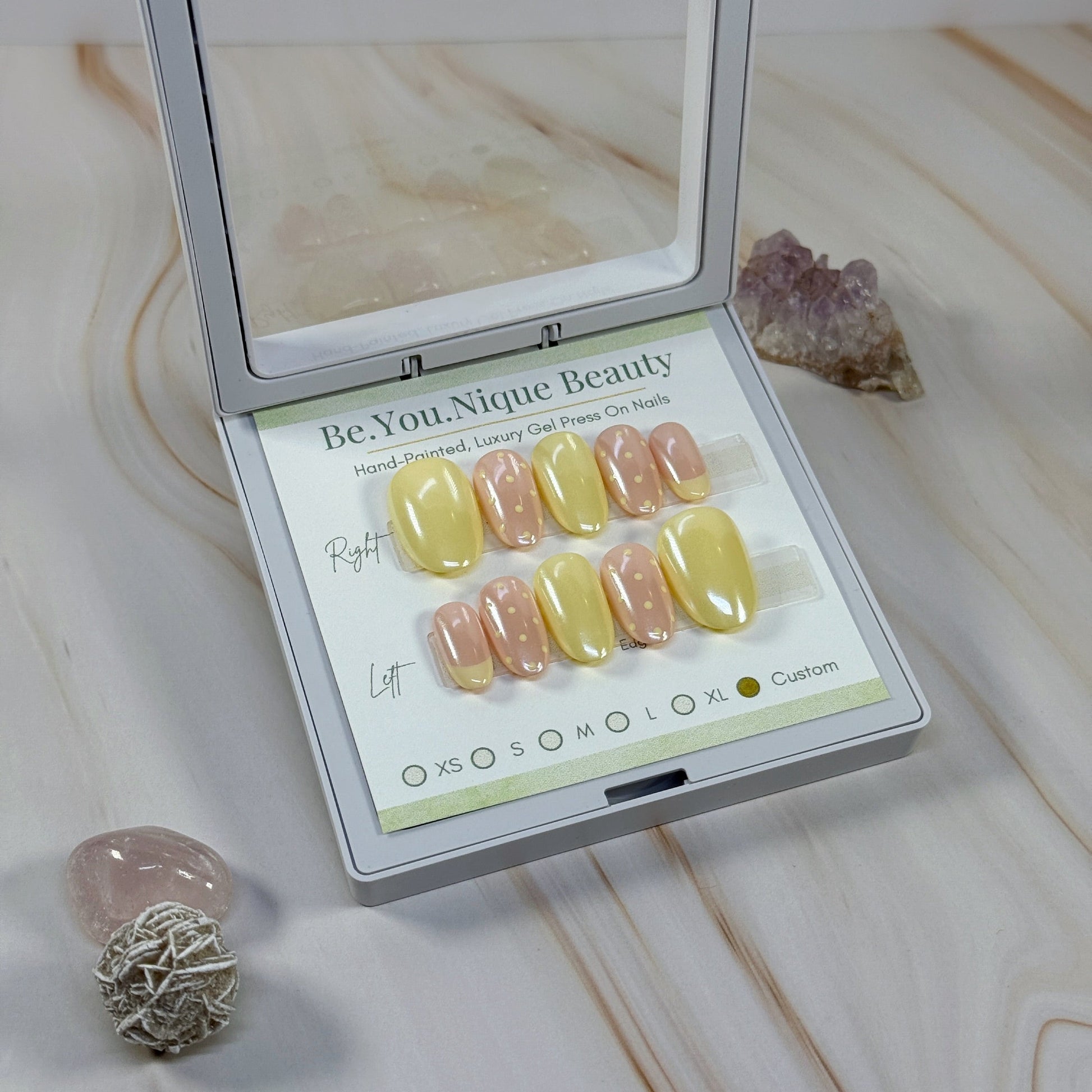 Set of yellow and neutral chrome nails with a single french accent nail and two polka dot accent nails per hand