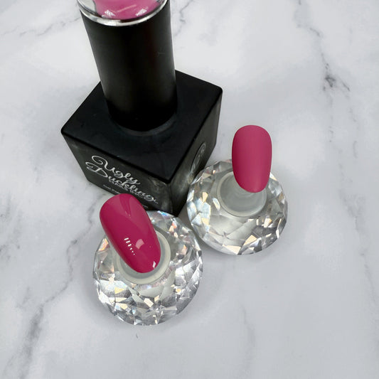 Nail polish bottle with pink top and two sample nails showing the colour with a matte and glossy topcoat on a marble surface.