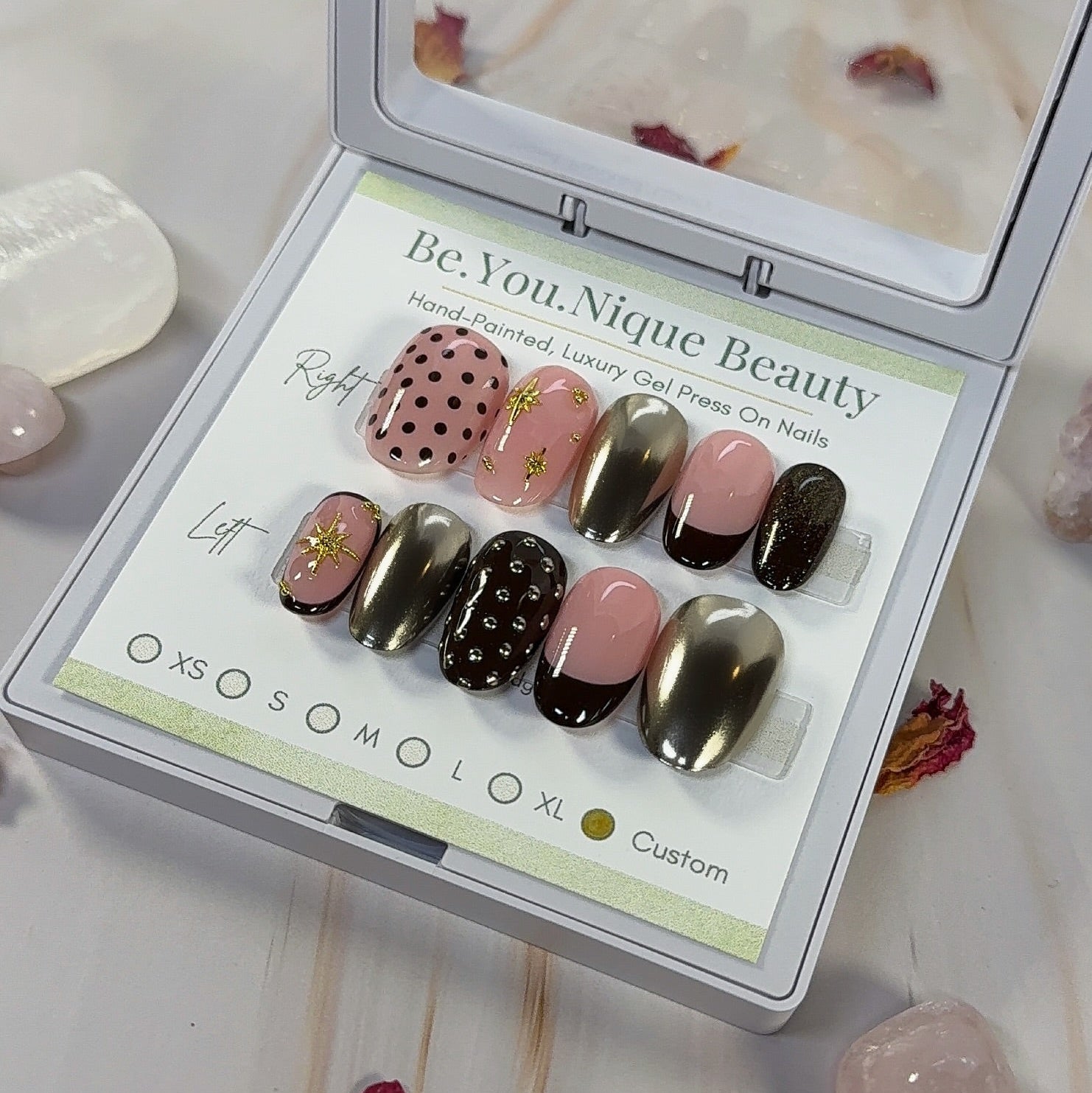 Custom Press on nail set in short round shape with a brown and gold chrome theme. this set features 3 gold chrome nails, 2 french tip nails with a deep brown tip, two nails with polka dots and 2 nails with gold star charms. the base colour is a peachy pink.