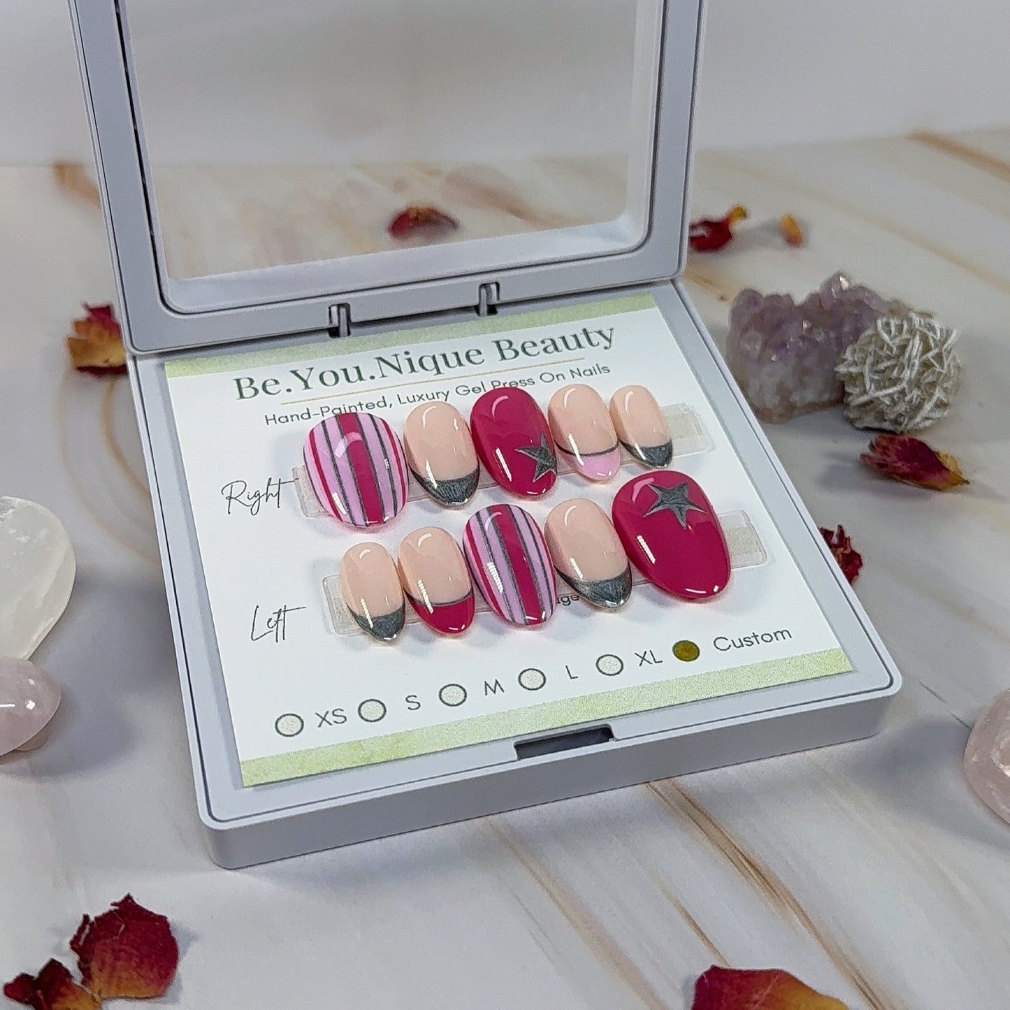 Set of reusable custom press on nails on a short almond nail. two tone pink with stripes and silver accents, pink and silver french tips and silver start accents. 