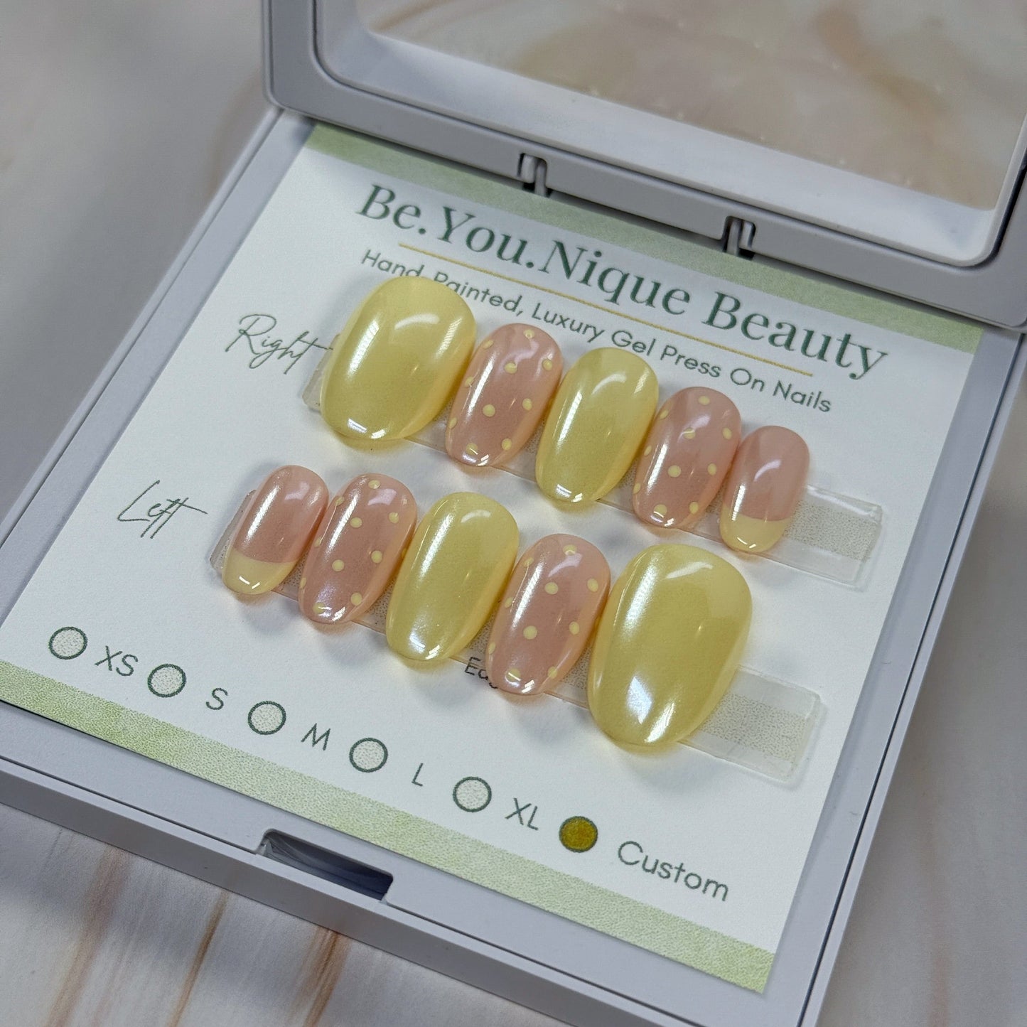 Set of yellow and neutral chrome nails with a single french accent nail and two polka dot accent nails per hand