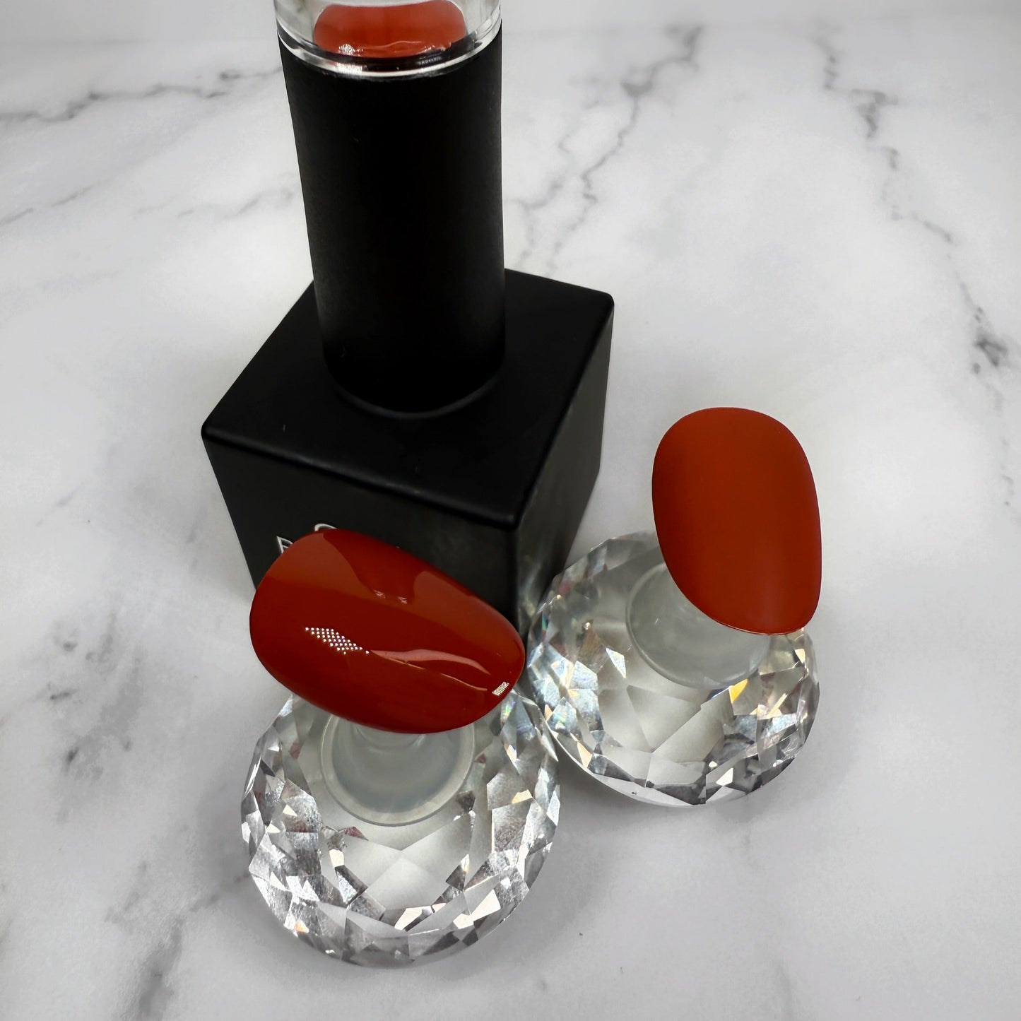 nail polish with two sample nails showing matte and glossy topcoat on a marble surface