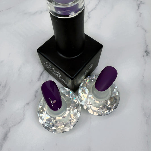 nail polish bottle with two sample nails showcasing a deep royal purple polish with a glossy and matte topcoat option.