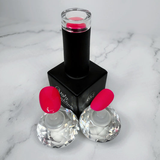 Black nail polish bottle with pink cap and two sample nails with glossy and matte top coats on a marble surface
