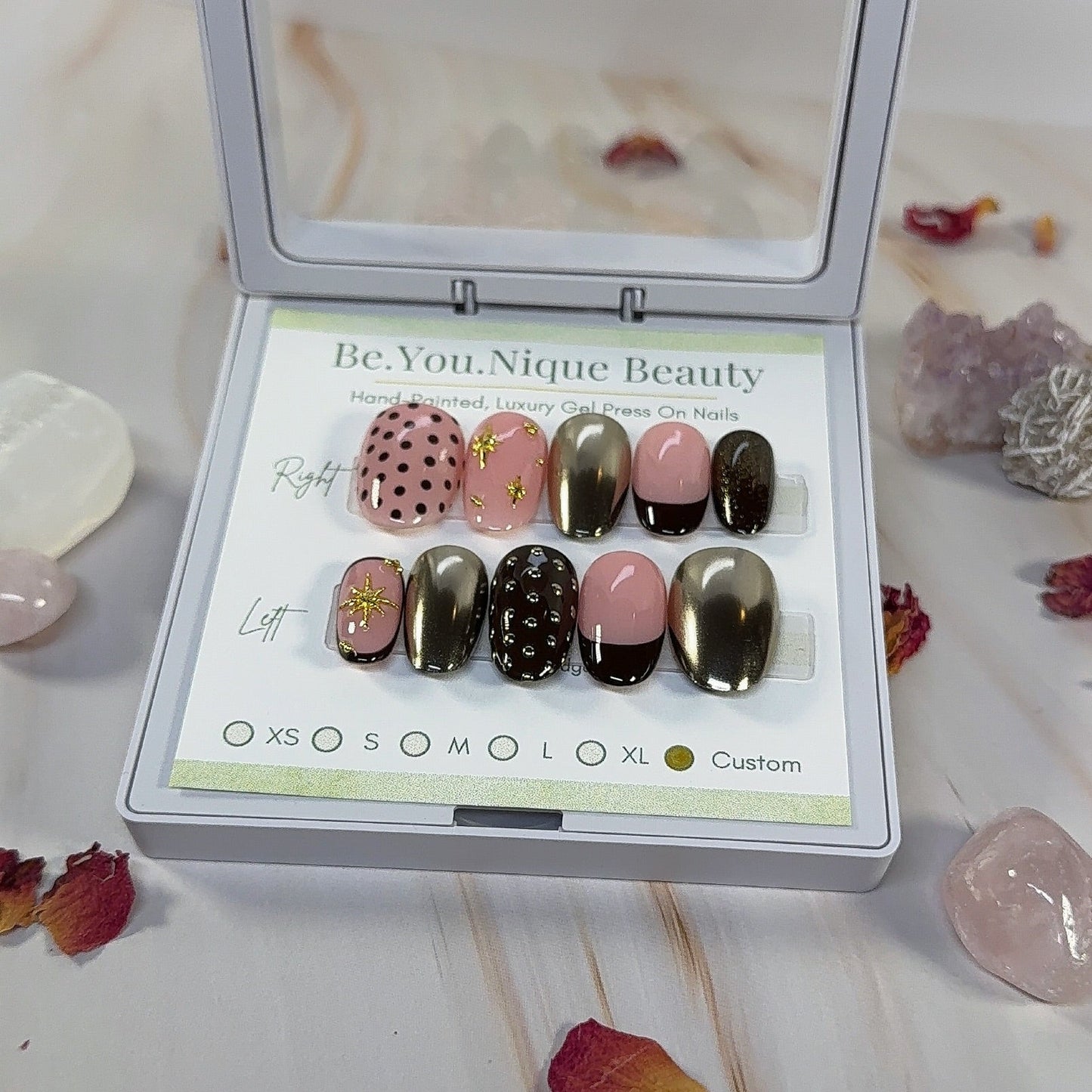 Custom Press on nail set in short round shape with a brown and gold chrome theme. this set features 3 gold chrome nails, 2 french tip nails with a deep brown tip, two nails with polka dots and 2 nails with gold star charms. the base colour is a peachy pink.