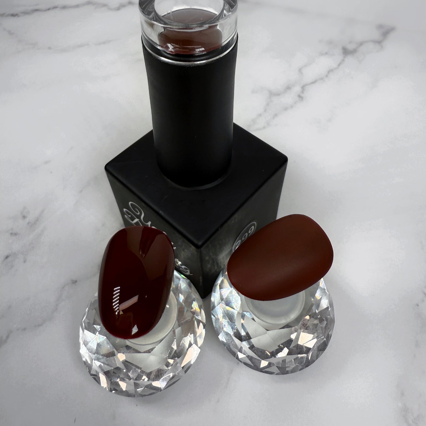 Nail polish bottle with two sample nails showing the brown colour with a glossy and matte topcoat on a marble surface