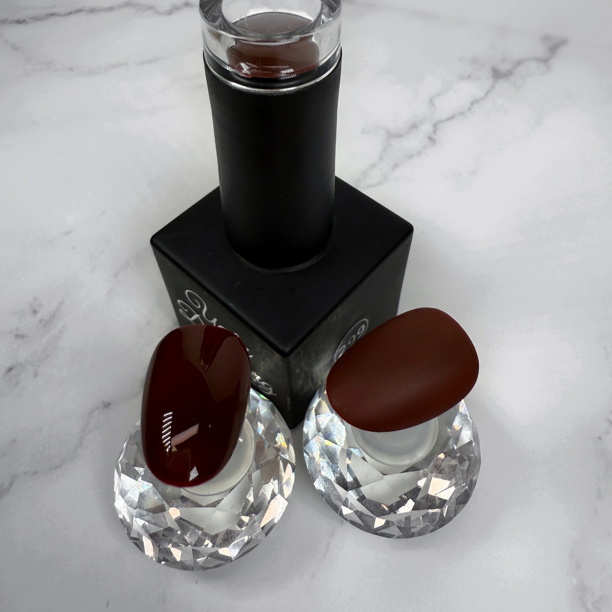 Nail polish bottle with two sample nails showing the brown colour with a glossy and matte topcoat on a marble surface