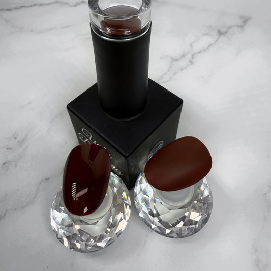 Nail polish bottle with two sample nails showing the brown colour with a glossy and matte topcoat on a marble surface