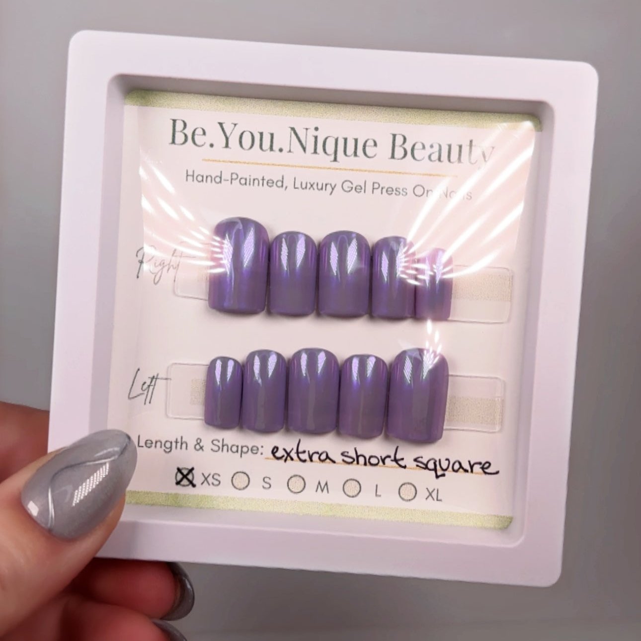 A set of extra short, square-shaped press-on nails in size extra small, featuring a vibrant purple base with an iridescent chrome finish. The nails have a sleek, reflective sheen that shifts in the light, adding a touch of bold elegance. Pre-designed and ready to apply with adhesive tabs, this set offers a stylish, easy-to-achieve manicure in a striking, futuristic color.