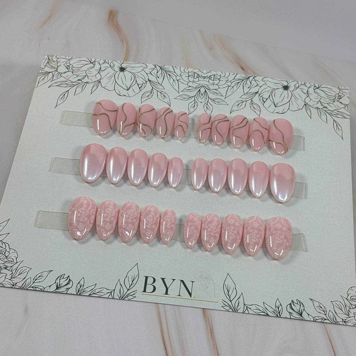 3 sets, a neutral with gold swirls, a chrome french fade and a neutral with subtle lace