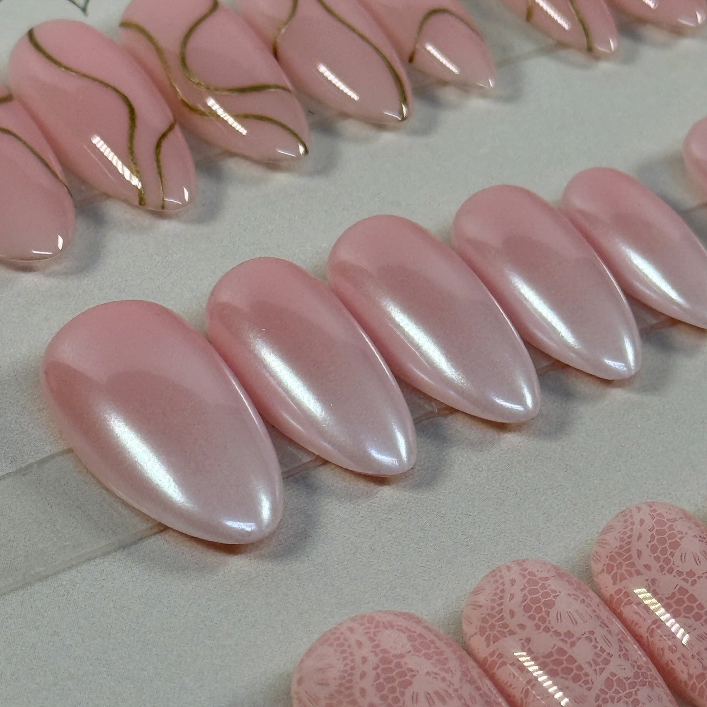 3 sets, a neutral with gold swirls, a chrome french fade and a neutral with subtle lace